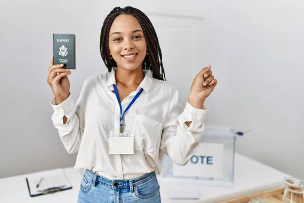 Young african american woman at political campaign election holding usa passport smiling happy pointing with hand and finger to the side