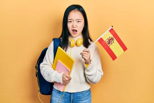 Молодая Китаянка Студентка Обмену Держит Испанский Флаг Руках Смотрит Скептически — стоковое фото