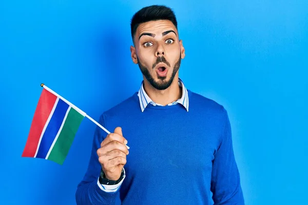 Ung Latinamerikansk Man Med Skägg Håller Gambia Flagga Rädd Och — Stockfoto