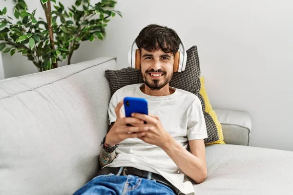 Jovem Hispânico Usando Smartphone Fones Ouvido Deitados Sofá Casa — Fotografia de Stock