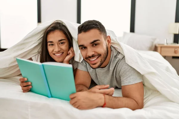 Jovem Casal Latino Leitura Livro Cobrindo Com Lençol Cama — Fotografia de Stock