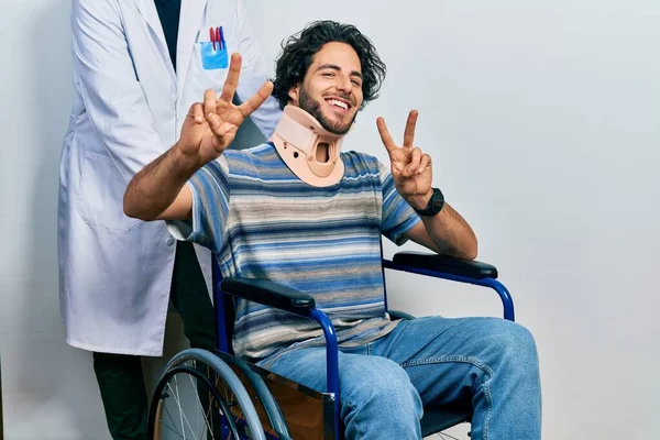 Tekerlekli Sandalyede Oturan Yakışıklı Boyunluk Takmış Gülümseyen Parmaklarını Zafer Işareti — Stok fotoğraf