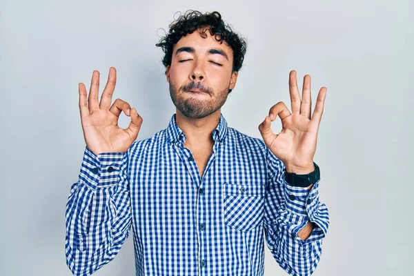 カジュアルな服を着た若いヒスパニック系の男がリラックスし 指で瞑想ジェスチャーを行う目を閉じて笑顔 ヨガのコンセプト — ストック写真