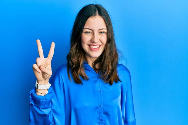 年轻的黑发女人穿着休闲的蓝色衬衫 带着自信和快乐的微笑 用手指指了指二号 — 图库照片