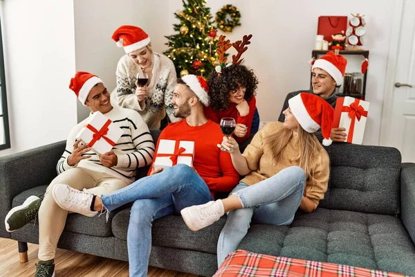Gruppo Giovani Che Festeggiano Natale Bevendo Vino Tenendo Regali Seduti — Foto Stock