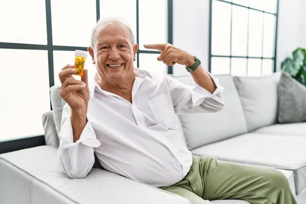 Starší Muž Držící Pilulky Úsměvem Ukazující Hlavu Jedním Prstem Skvělý — Stock fotografie