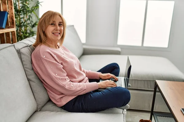 Blonde Frau Mittleren Alters Sitzt Mit Laptop Auf Dem Sofa — Stockfoto