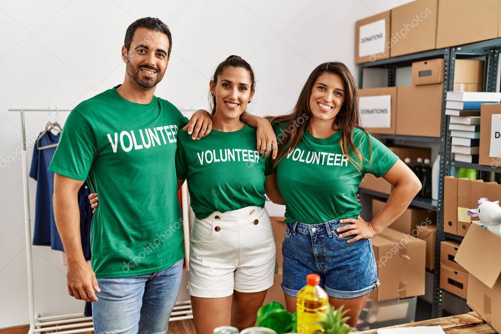 Group of hispanic volunteers smiling happy standing at charity center.