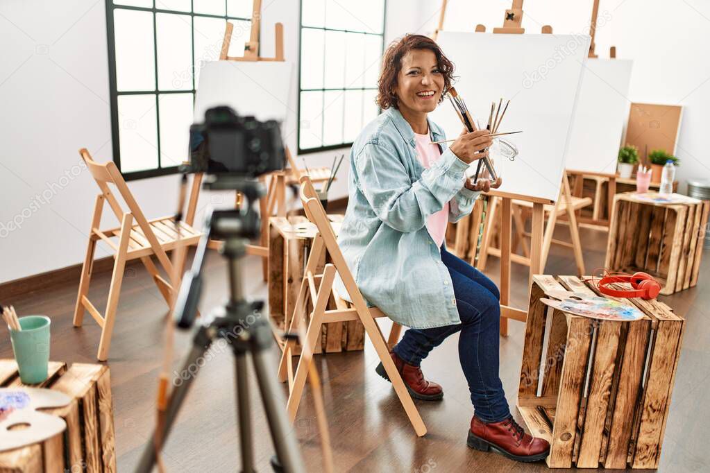 Middle age hispanic artist blogger smiling happy having video call at art studio.