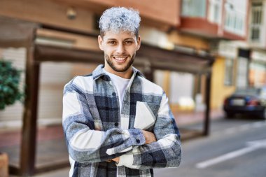 Genç İspanyol adam mutlu bir şekilde gülümsüyor şehirde çapraz hareketlerle.