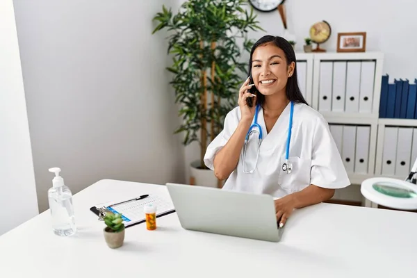 Jovem Latina Vestindo Uniforme Médico Falando Smartphone Clínica — Fotografia de Stock