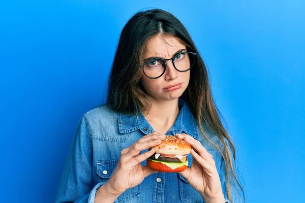 Νεαρή Καυκάσια Γυναίκα Τρώει Ένα Νόστιμο Κλασικό Burger Σκεπτικιστής Και — Φωτογραφία Αρχείου