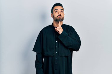 Sakallı, Katolik rahip cübbesi giyen yakışıklı İspanyol bir adam. Düşünceleri şüphe üzerine yoğunlaşmıştı. Parmakları çenesinde ve yukarı bakıyordu. 