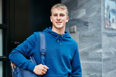 Üniversitede mutlu bir şekilde gülümseyen genç sarışın öğrenci..