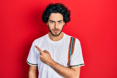 Yakışıklı ispanyol adam parmaklarını kenarı göstererek şüpheci ve gergin, sorun yüzünden suratını asıyor. negatif kişi. 