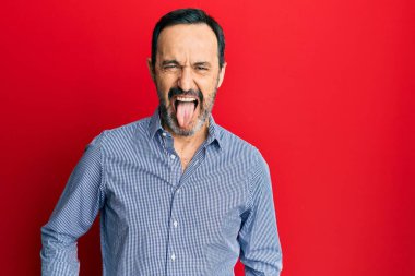 Orta yaşlı İspanyol bir adam günlük kıyafetler giyip komik bir ifadeyle dilini dışarı çıkarıyor. duygu kavramı. 