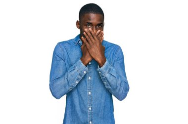 Gündelik giysiler giyen genç Afro-Amerikan bir adam yanlışlıkla elleri ile ağzını kapatırken şok oldu. gizli kavram. 