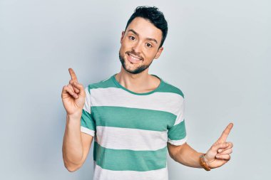 Gündelik kıyafetler giyen, kendine güvenen, parmaklarını farklı yönlere çeviren genç İspanyol adam. reklam için kopyalama alanı 