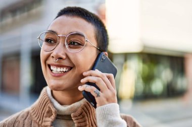 Kısa saçlı, gülümseyen, telefonda konuşan genç İspanyol kadın.