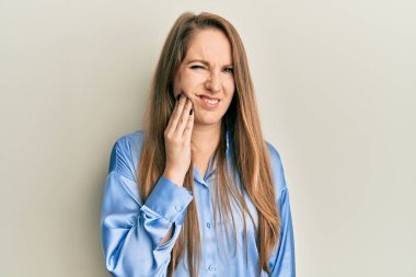 Dişlerinin ağrıması ya da diş hastalığından dolayı elleri ve elleri birbirine değen sıradan mavi tişörtlü genç sarışın bir kadın. dişçi 