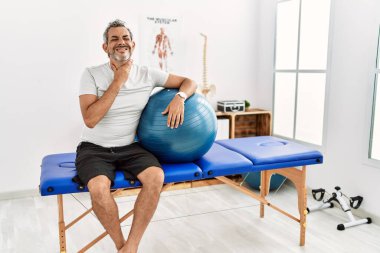Orta yaşlı İspanyol adam ağrı kesici kliniğinde elinde pilates topu tutarken boynu ağrıyan, boğazı ağrıyan, grip, mantar ve enfeksiyon kapmış. 