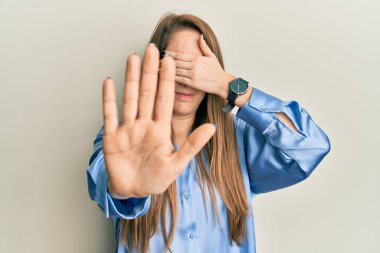 Sıradan mavi tişört giyen genç sarışın kadın elleriyle gözlerini kapatıyor ve üzgün ve korku ifadeleriyle dur hareketi yapıyor. utangaç ve olumsuz kavram. 