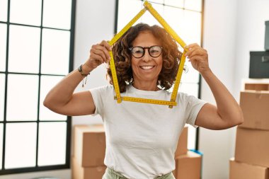 Orta yaşlı İspanyol kadın gülümsüyor. Ev projesinde kendine güveni tam.