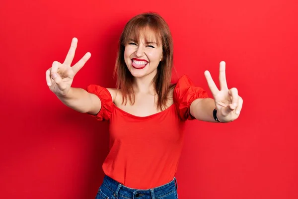 Kırmızı Tişörtlü Kızıl Saçlı Genç Bir Kadın Elini Göstererek Gülümsüyor — Stok fotoğraf
