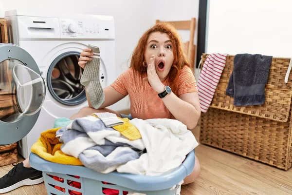 汚い洗濯機の手に汚れた洗濯機を置く若い赤毛の女性口の中に秘密噂を伝え 悪意のある話の会話をささやく — ストック写真