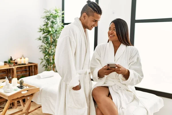 Young Latin Couple Wearing Bathrobe Using Smartphone Beauty Center — Stock Photo, Image