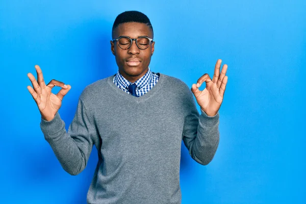 ビジネススタイルを身に着けている若いアフリカ系アメリカ人の男性と眼鏡をリラックスし 目を閉じて指で瞑想ジェスチャーを行う笑顔 ヨガのコンセプト — ストック写真