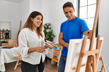 Öğrenci ve öğretmen resim yaparken gülümsüyor..