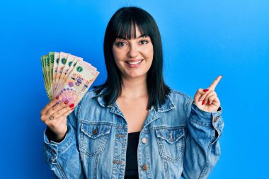 Arjantinli banknotlar tutan genç İspanyol kadın mutlu bir şekilde gülümsüyor. 