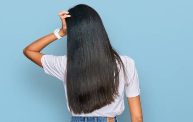 Güzel, genç Asyalı bir kadın, günlük beyaz tişörtünü ters giymiş, elleri kafasında şüpheyi düşünüyor. 