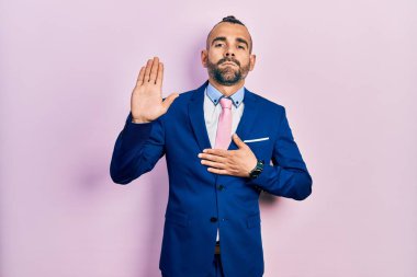 Genç İspanyol bir adam iş elbisesi ve kravat takıyor. Göğüs ve avuçlar açık yemin ediyor. Sadakat yemini ediyor. 