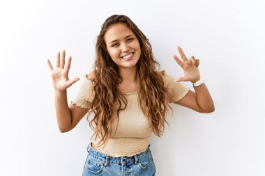 Güzel İspanyol kadın tecrit edilmiş vaziyette dikilirken arka planda sekiz numaralı parmaklarıyla işaret ederken kendinden emin ve mutlu bir şekilde gülümsüyor.. 