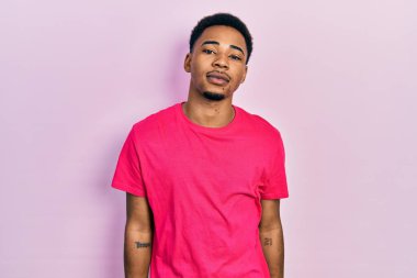 Casua tişörtü giyen genç Afro-Amerikan adam yüzünde ciddi bir ifadeyle rahatladı. Basit ve doğal bir şekilde kameraya bakıyorsun.. 