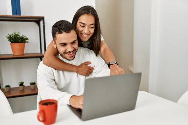 Laptop kullanan ve evde kahve içen genç bir çift..