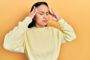 Burun piercingli, eli kafasında sıradan sarı bir kazak giyen güzel İspanyol kadın. Stres yüzünden baş ağrısı çekiyor. migren ağrısı. 