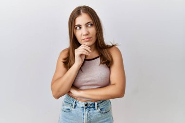 Genç esmer kadın, soyutlanmış arka planda, elleri çenesinde soru sorarken, düşünceli bir ifade takınıyor. Düşünceli bir yüzle gülümsüyor. şüphe kavramı. 