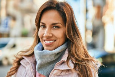 Genç İspanyol kadın gülümseyerek şehirde mutlu mesut dikiliyor..