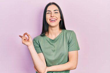 Mavi gözlü, sıradan tişörtlü, yüzünde kocaman bir gülümseme olan, eli ve parmağı kameraya bakan güzel bir kadın.. 