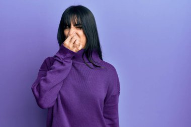 Kâküllü, balıkçı yaka kazak giyen genç esmer kadın pis ve iğrenç bir koku alıyor. Nefesini burnunda tutuyor. Kötü kokuyor. 