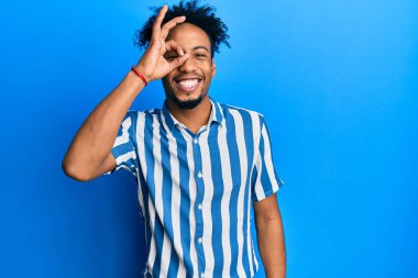 Sakallı, sıradan çizgili gömlek giyen, el hareketleriyle gülümseyen, gözleriyle gülen, mutlu yüzlü, Afro-Amerikan genç adam.. 