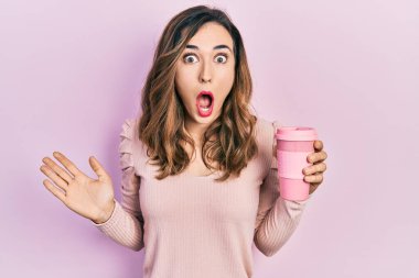 Genç İspanyol kız elinde kahve tutuyor. Korkmuş ve ağzı açık, şaşırmış ve şaşırmış. 