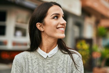 Genç İspanyol kadın gülümseyerek şehirde mutlu mesut dikiliyor..