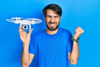 İHA 'yı tutan genç İspanyol adam gururla haykırıyor, zaferi ve başarıyı kutluyor. 