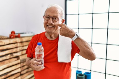 Spor giysisi ve havlu giyen son sınıf öğrencisi el ve el parmaklarıyla ve burunla işaret ediyor, neşeli bir şekilde gülümsüyor. güzellik konsepti 