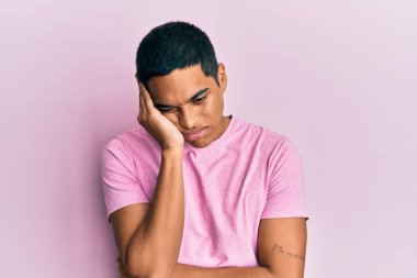 Genç, yakışıklı, pembe tişört giyen, yorgun ve bunalımda kollarını kavuşturmaktan sıkılmış görünen bir İspanyol.. 