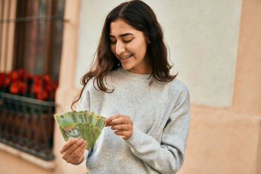 Orta Doğulu genç kız gülümsüyor Şili pesolarını sayarak şehirde.